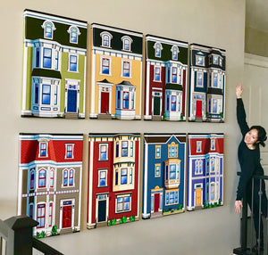   Photo of 8 jellybean row canvas on a wall with a smiling woman standing next to them arms outstretched 